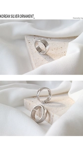 Detailed view of adjustable minimalist silver ring on smooth stone and silk background