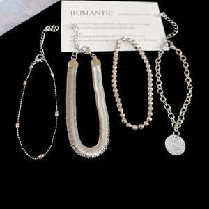 Dettaglio di braccialetti in argento con catena a serpente e perline con ciondolo tondo
