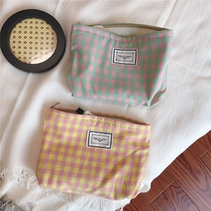 Close-up of checkered cotton makeup bags with Time to Party label on white fringe rug
