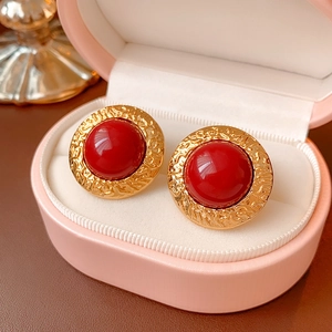 Macro detail of vintage gold earrings with red stones in a pink jewelry gift box