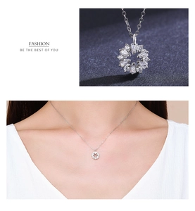 Macro detail of S925 silver flower pendant necklace with diamonds on a female model