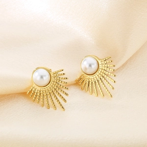 Vintage gold sunburst pearl earrings displayed on elegant champagne silk fabric background