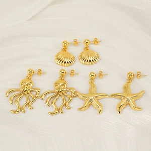 Detalle de pendientes de acero chapado en oro 18k con formas de concha y estrella de mar