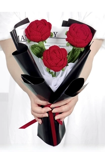 Handcrafted bouquet of three red knitted roses in newspaper wrap with a red ribbon