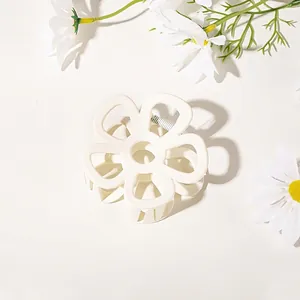 Close-up of cream-colored floral claw clip with matte texture and metal spring mechanism