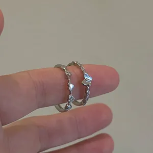 Close-up of silver rings set with pavé zircon heart and butterfly designs on finger