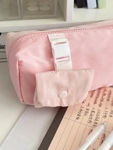Pink quilted pencil case detail showing adjustable white buckle strap and front button pocket