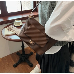 Close-up of brown pleated crossbody bag with golden twist lock and flap design
