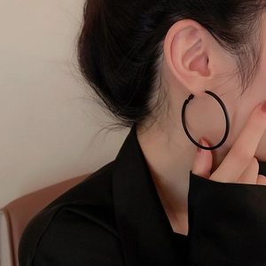 Close-up of model wearing a minimalist black metal hoop earring with matte finish