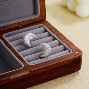 Elegant silver crescent earrings with frosted granular texture in a walnut jewelry box
