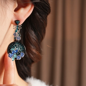 Dettaglio di orecchini pipa vintage con strass blu e rifiniture floreali in smalto