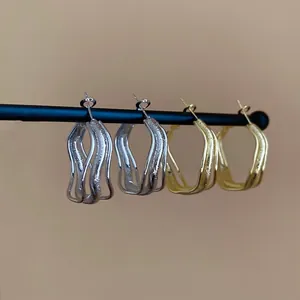 Textured gold and silver irregular wave hoop earrings with a matte brushed metallic finish
