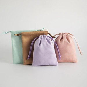Macro detail of soft suede drawstring jewelry pouches in mint, tan, lilac, and pink