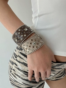 Detail of wide leather bracelets with crystal rhinestones and metal studs in punk style