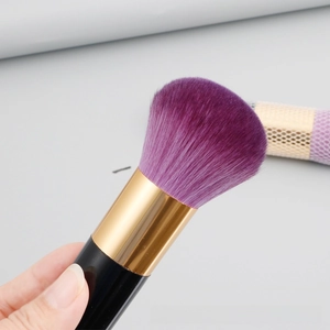 Detail of soft purple gradient synthetic bristles and gold metal ferrule of the makeup brush