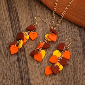 Autumn themed jewelry set with colorful maple leaf earrings and necklace on wood