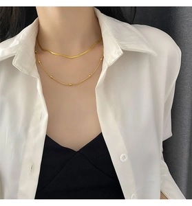 Close-up of a double-layered gold flat snake chain necklace with beads on a model