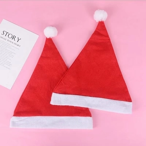 Close-up of two red non-woven Christmas hats with white trim on a pink background