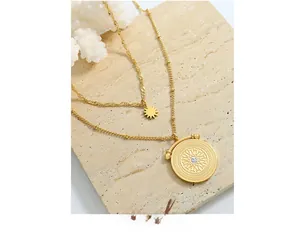 Close-up of double-layer gold necklace with starburst sun pendants and zircon on stone