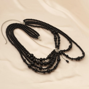 Detail of multi-layer black beaded body chain with silver lobster clasp on silk