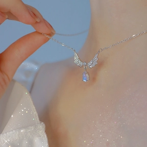 Silver angel wing necklace with blue moonstone teardrop pendant worn by model