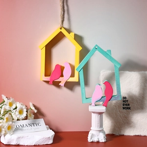 Detail of colorful wooden bird figurines in yellow and green house frames for home decor