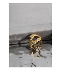 Dettaglio macro di anello in argento dorato con trama irregolare e micro-set di zirconi