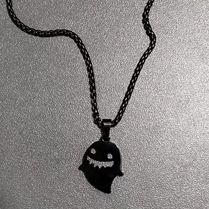 Close-up of black metal ghost pendant necklace with a smiling face for Halloween