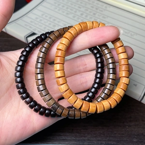 Bracelets en bois naturel d'ébène et de santal vert tenus à la main sur bureau en bois