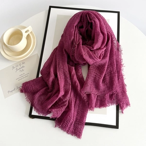 Detail of magenta linen scarf texture showing pleated fabric and frayed edges for summer wear