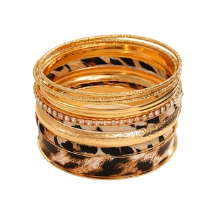 Detail van een meerlaagse gouden armbandset met luipaardprint en fonkelende strassteentjes