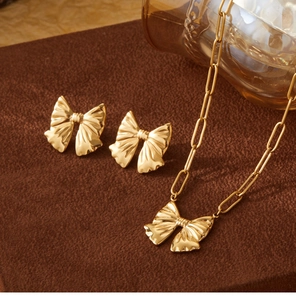 Detailed close-up of golden bow-knot necklace and earrings jewelry set on brown velvet