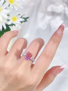 Macro detail of rectangle pink gemstone ring with side diamond accents on model hand
