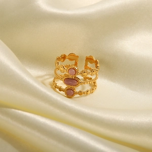 Eleganter goldener mehrlagiger offener Ring mit rosa Ovalsteinen auf Satinstoff