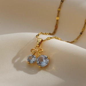 Close-up of golden cherry necklace with sparkling zircon stones and bow detail on silk
