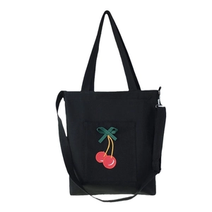 Black canvas tote bag with embroidered cherry and green bow, featuring dual straps