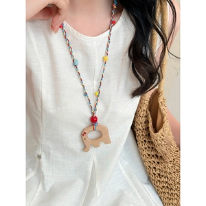 Gros plan du collier éléphant en bois avec corde tressée colorée sur un mannequin