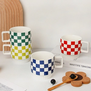 Macro view of four colorful checkered ceramic mugs with square handles and striped bases