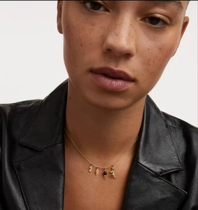 Detail of s925 silver gold-plated necklace with number pendants and blue gemstone on a model