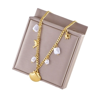 Gold ocean style pearl necklace with dolphin and shell pendants on a jewelry box