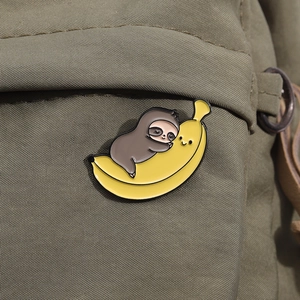 Detail of cute sloth hugging a banana enamel pin attached to a green canvas bag