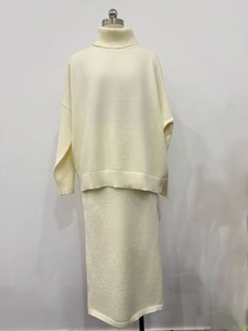 Détail du pull en tricot à col montant et de la jupe longue en maille crème beige