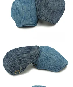 Detail showing the adjustable metal buckle and blue patterned denim texture of the beret cap