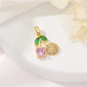 Macro shot of 14k gold cherry pendant with pink and green zircon stones on white silk