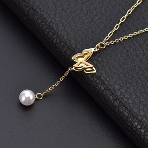 Minimalist golden butterfly pendant necklace with single pearl detail on leather background