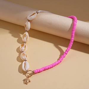 Detail of bohemian necklace with white shells, pink beads, and a golden sea turtle charm