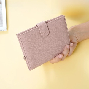 Close-up of pink litchi grain leather passport holder with gold D-ring buckle
