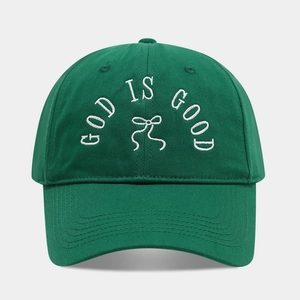 Close-up of green cotton baseball cap with white GOD IS GOOD embroidery and bow detail