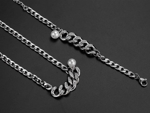 Detailed macro view of silver Cuban chain necklace with embedded rhinestones and white pearls