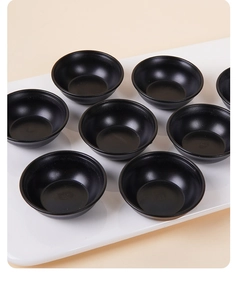Close-up of mini black matte sauce dishes arranged on a white serving tray for dollhouses